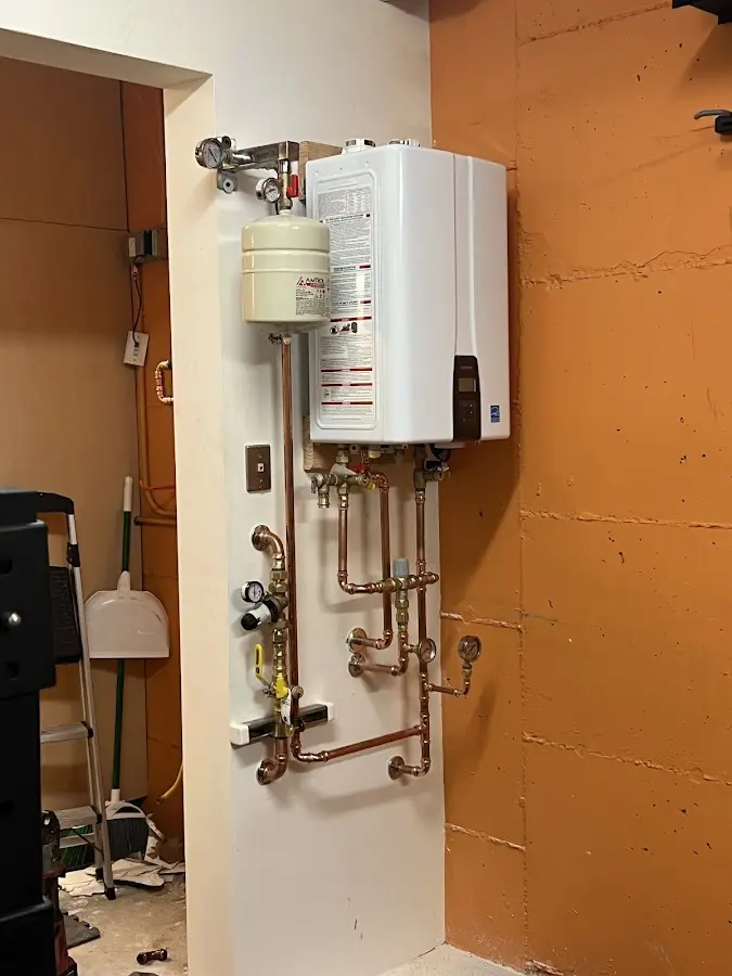 Plumbing technician inspecting water heater connections in Saranac